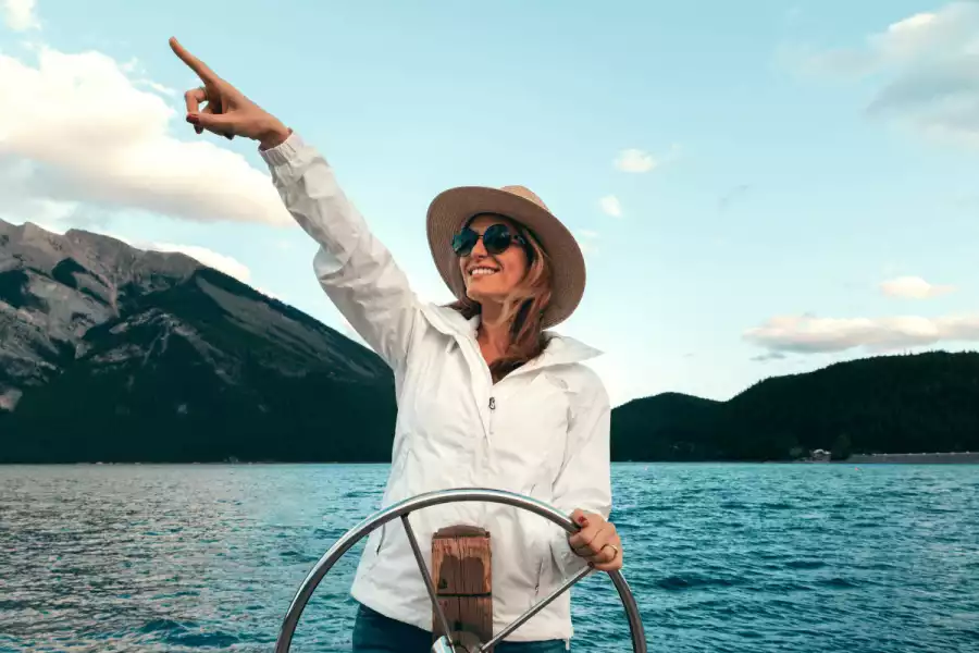 Sretna žena koja upravlja brodom i pokazuje prstom smjer gdje treba krenuti je analogija za upravljanje uspješnim poslovanjem.