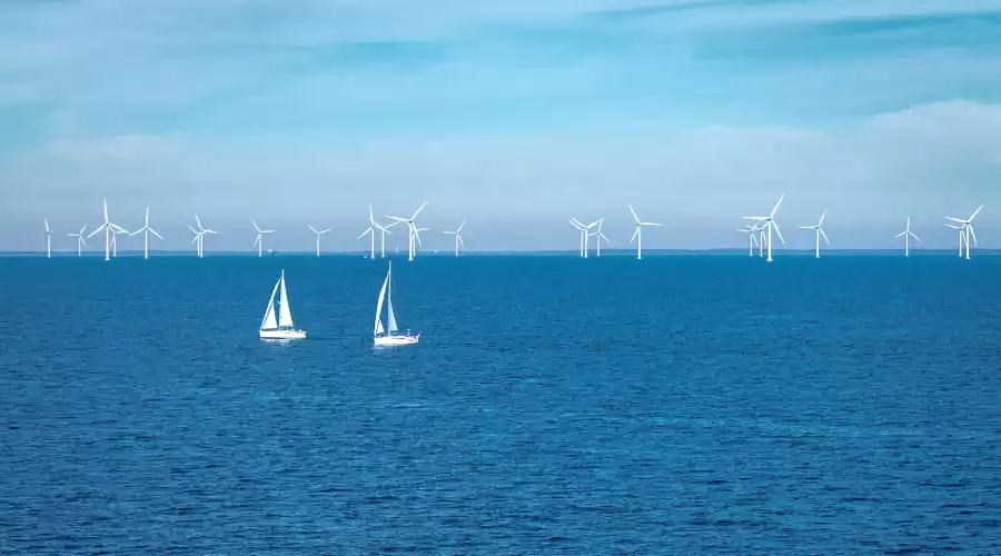 Jedrilice plove uz vjetrenjače na moru. Nautički turizam treba promovirati održivost i zaštitu okoliša.