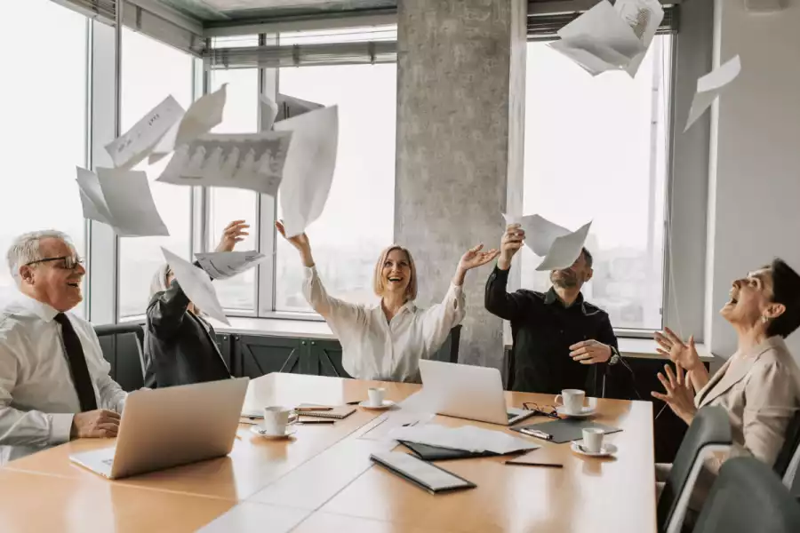 Pet zaposlenika u uredu bacaju papire u zrak u znak sreće
