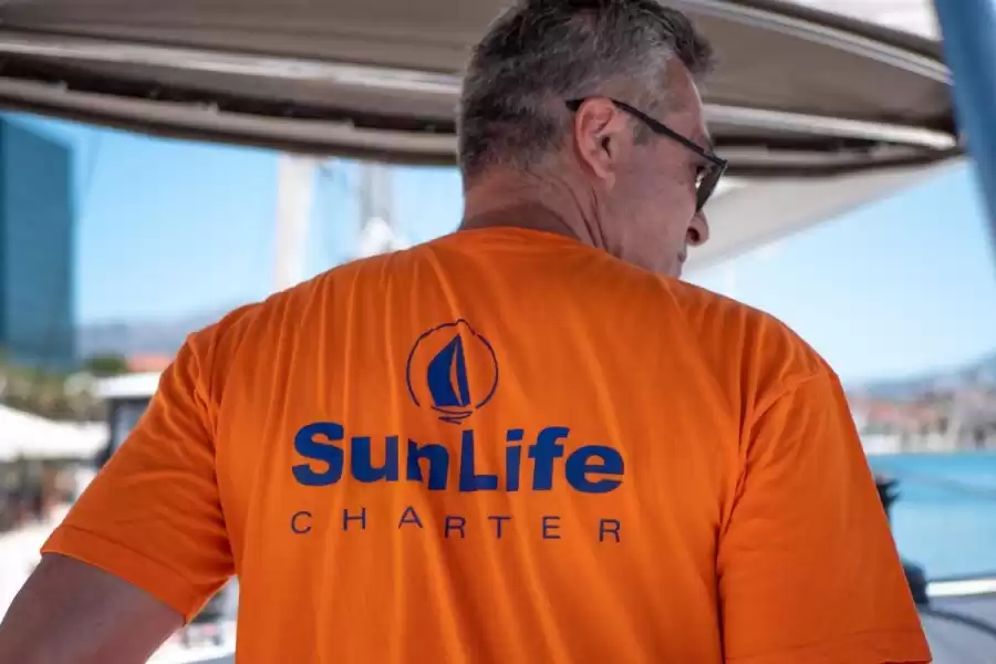 Djelatnik SunLife Chartera u brendiranoj majici čartera njihove karakteristične narančaste boje.