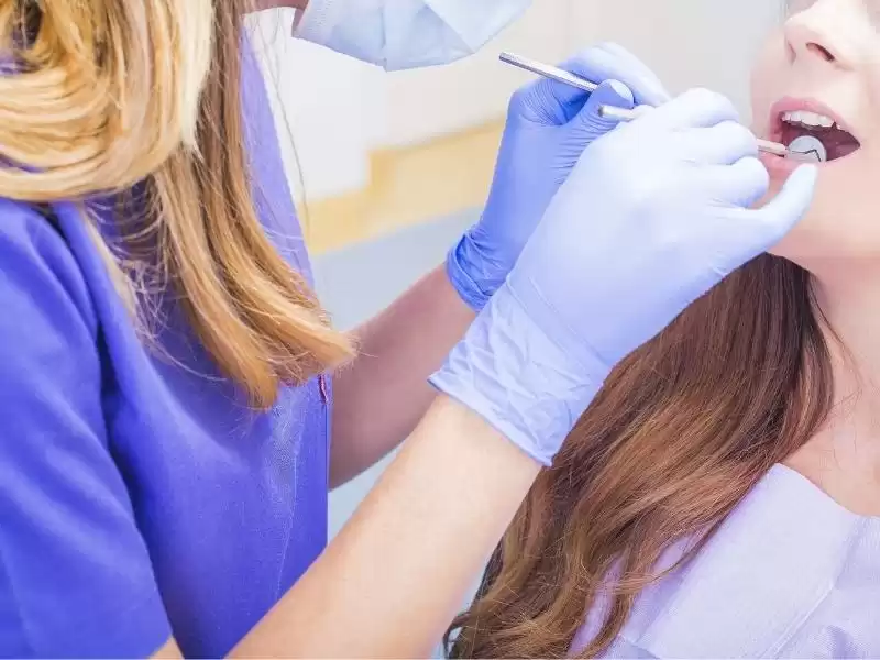 Zubarica pregledava zube ženi na prvom besplatnom pregledu.
